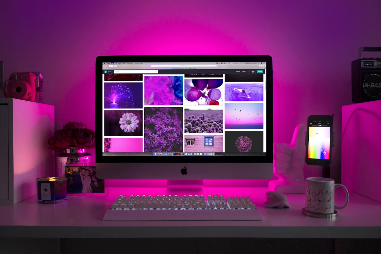 Oferta Modern desk setup with neon lighting and a desktop computer displaying colorful images.